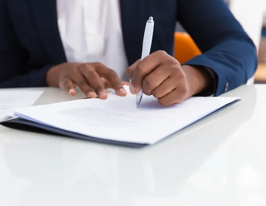 Paralegal seated at desk taking notes with pen and paper